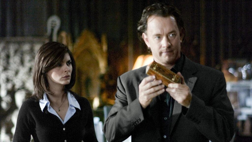 Robert Langdon (Tom Hanks) und Sophie Neveu (Audrey Tautou) untersuchen in „The Da Vinci Code – Sakrileg“ (2006) den hölzernen Kryptex. Während Langdon das rätselhafte Behältnis aufmerksam in den Händen hält, verfolgt Sophie konzentriert jeden Schritt ihrer gemeinsamen Suche nach dem Geheimnis des Heiligen Grals.