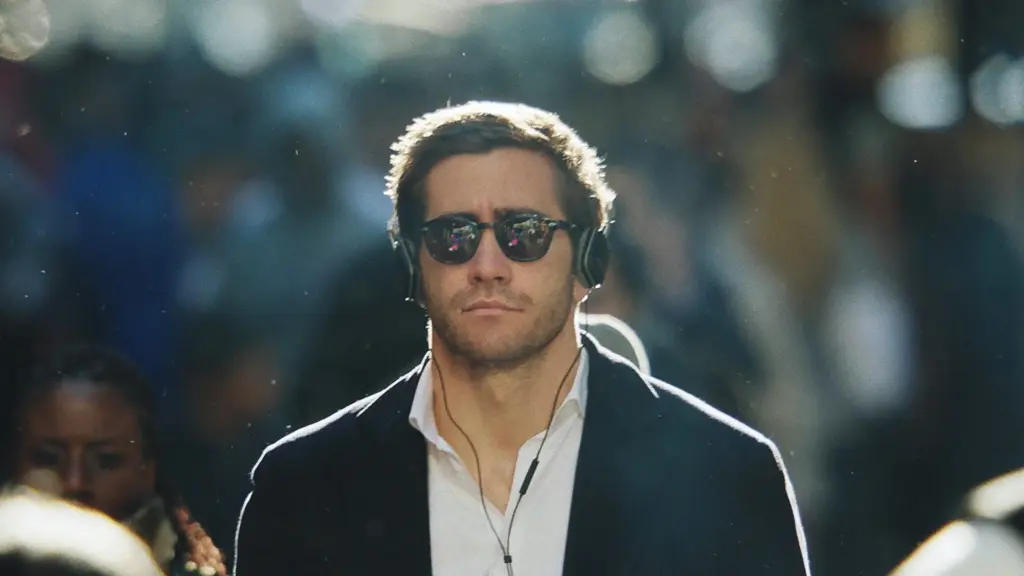 Davis Mitchell (Jake Gyllenhaal) geht mit nachdenklichem, ausdruckslosem Gesichtsausdruck direkt auf die Kamera zu. Er trägt ein weißes, leicht geöffnetes Hemd, ein dunkles Sakko, eine dunkle Sonnenbrille und große Kopfhörer über den Ohren. Um ihn herum herrscht ein unscharfes, dichtes Menschengedränge, das die emotionale Entfremdung und Isolation des Protagonisten inmitten der geschäftigen Großstadt unterstreicht. | FYP Filme
