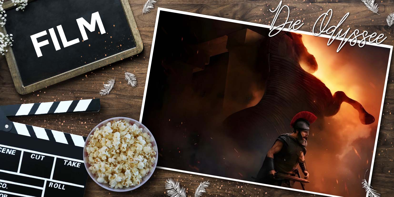 Auf einer Holzoberfläche liegen ein Filmklappenbrett, eine Schüssel Popcorn und eine kleine Tafel mit dem Wort Film. Rechts daneben ist ein Poster zu sehen, das Matt Damon als Odysseus zeigt: Er trägt antike Rüstung mit rotem Helmbusch und hält ein Schwert. Hinter ihm brennt das trojanische Pferd, dessen hölzerne Struktur in Flammen und Rauch aufgeht. Der Titel „Die Odyssee“ ist sichtbar, dazu die Credits „© Syncopy Inc. | Universal Pictures“ und die Website „www.passion-of-arts.de“. Die Komposition verbindet klassische Mythologie mit moderner Filmästhetik.