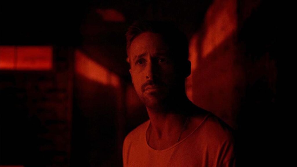 Julian, gespielt von Ryan Gosling, steht in einem rot ausgeleuchteten Korridor und blickt ernst nach vorn; eine stilisierte, düstere Szene aus dem Film Only God Forgives. | Top 5 Filme mit exotischen Schauplätzen