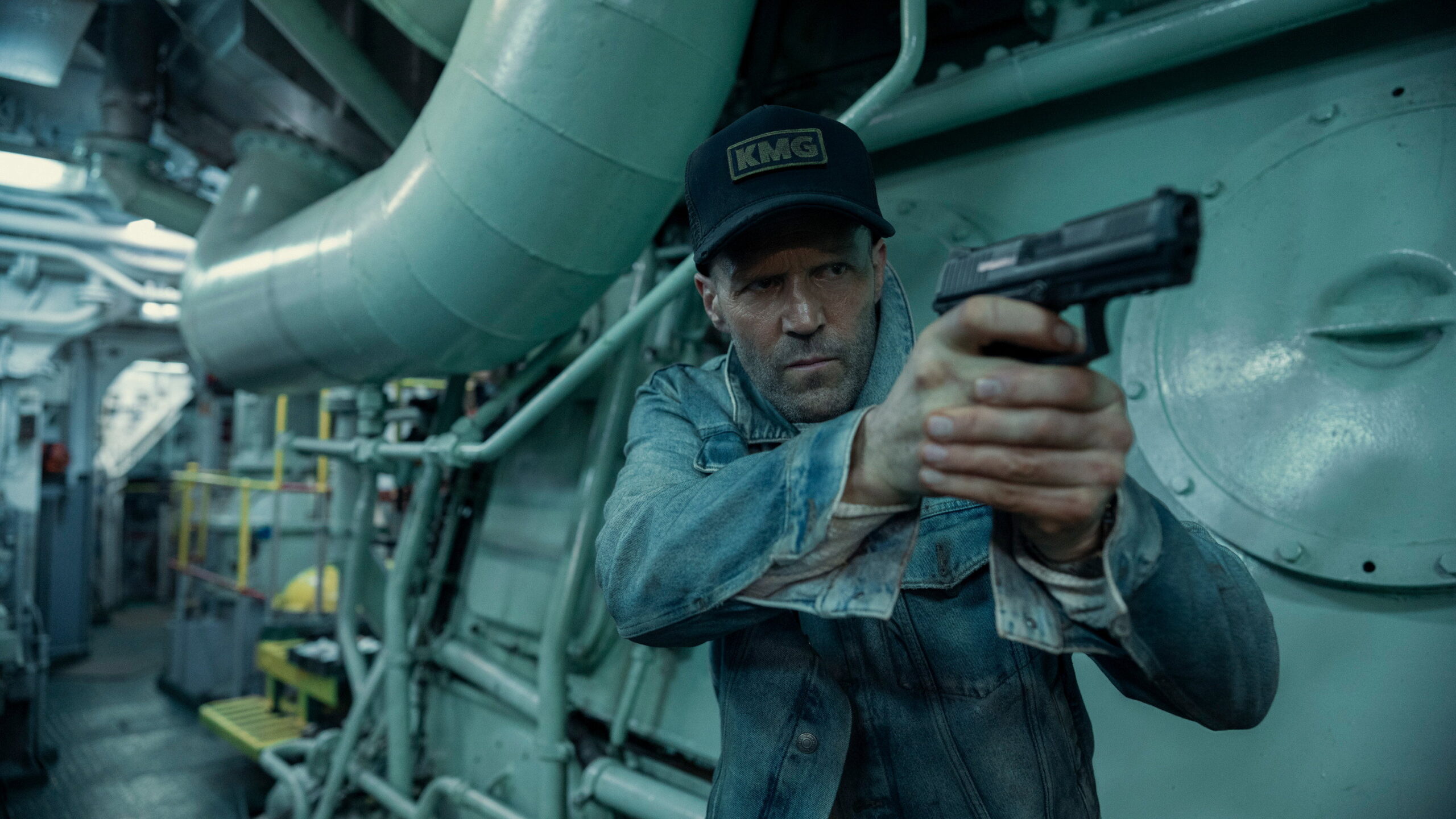 Das Bild zeigt Jason Stathman mit einer Pistole in einem Maschinenraum in einer Szene des Films Mutiny.