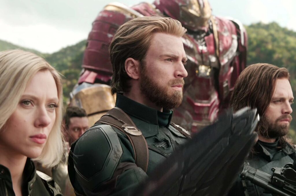 Das Bild zeigt in der Mitte Chris Evans als Captain America, links neben ihm Scarlett Johansson als Black Widow, an seiner rechten Seite Sebastian Stan als Winter Solider und dahinter Matt Bomer in einer Iron Man Rüstung. Das Bild zeigt die ausgestoßenen Avengers, die sich bereit für den Infinity War machen