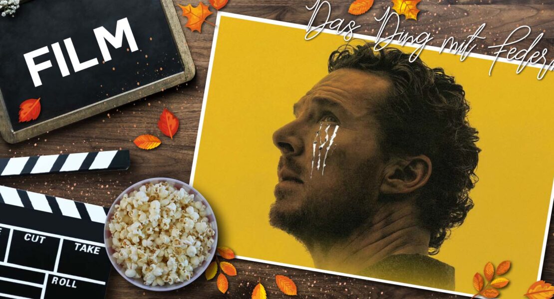 Herbstlich gestaltete Filmgrafik auf einem Holztisch: Links befinden sich eine Filmklappe, eine Schale mit Popcorn und eine Tafel mit der Aufschrift „FILM“. Rechts ist ein Porträt von Benedict Cumberbatch vor gelbem Hintergrund zu sehen. Über dem Bild steht der Schriftzug „Das Ding mit Federn“. Verstreute Herbstblätter und dekorative Lichteffekte rahmen die Komposition ein.