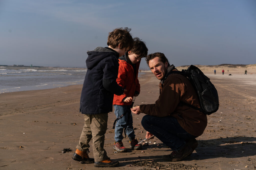 Das Bild zeigt eine Szene am Strand aus dem Film "Das Ding mit Federn". Zu sehen sind Henry Boxall, Benedict Cumberbatch und Richard Boxall
