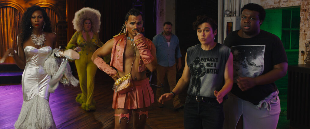 Verschiedene Charaktere aus dem Film Queens of the Dead stehen im Club und schauen gebannt in die Kamera. | Queens of the Dead – Filmkritik