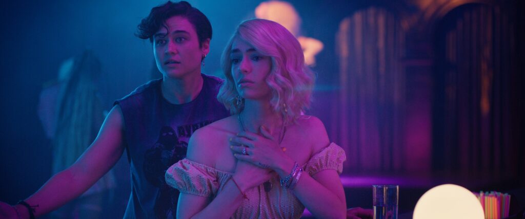 Zwei Personen stehen im Neonlicht eines Clubs.