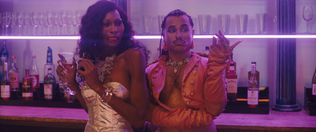 Zwei Personen stehen an einer Bar, eine schaut teilnahmslos, die andere erschreckt. | Queens of the Dead – Filmkritik