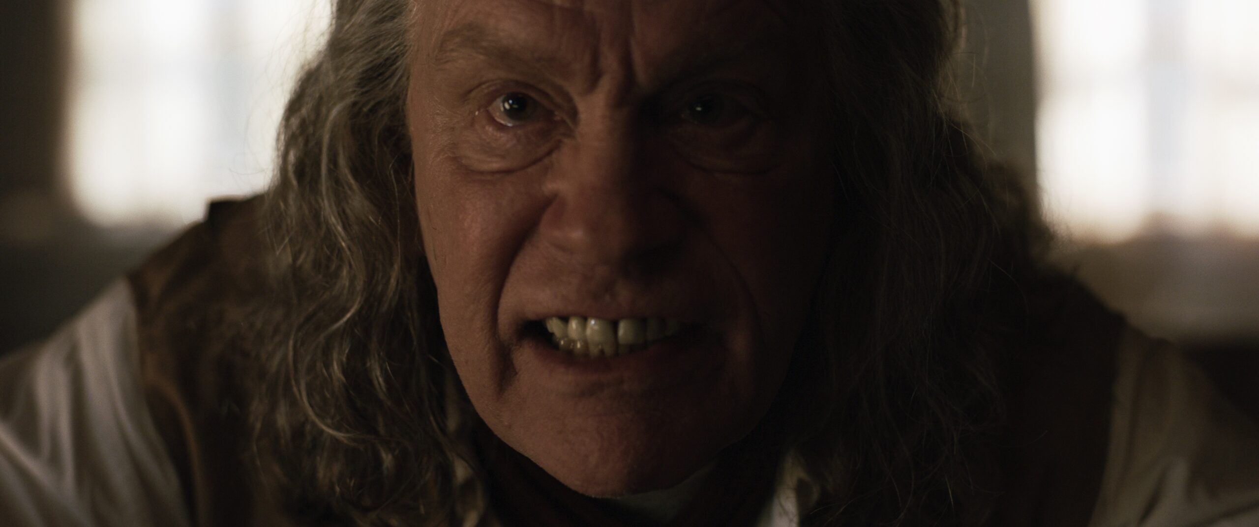 Das Bild zeigt John Malkovich mit intensivem Blick, nah an sein Gesicht gefilmt.