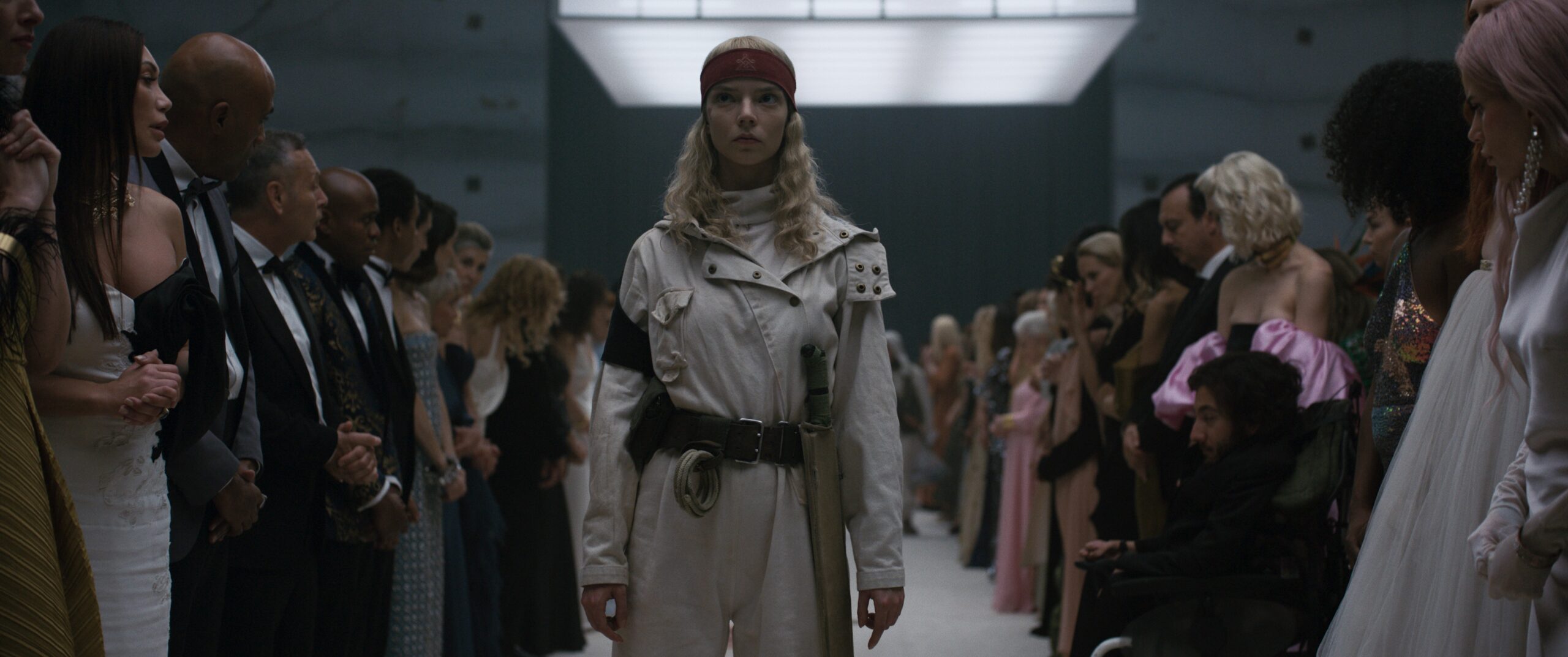 Das Bild zeigt Joan (Anya Taylor-Joy) in der Mitte zwischen zwei Menschenreihen stehen